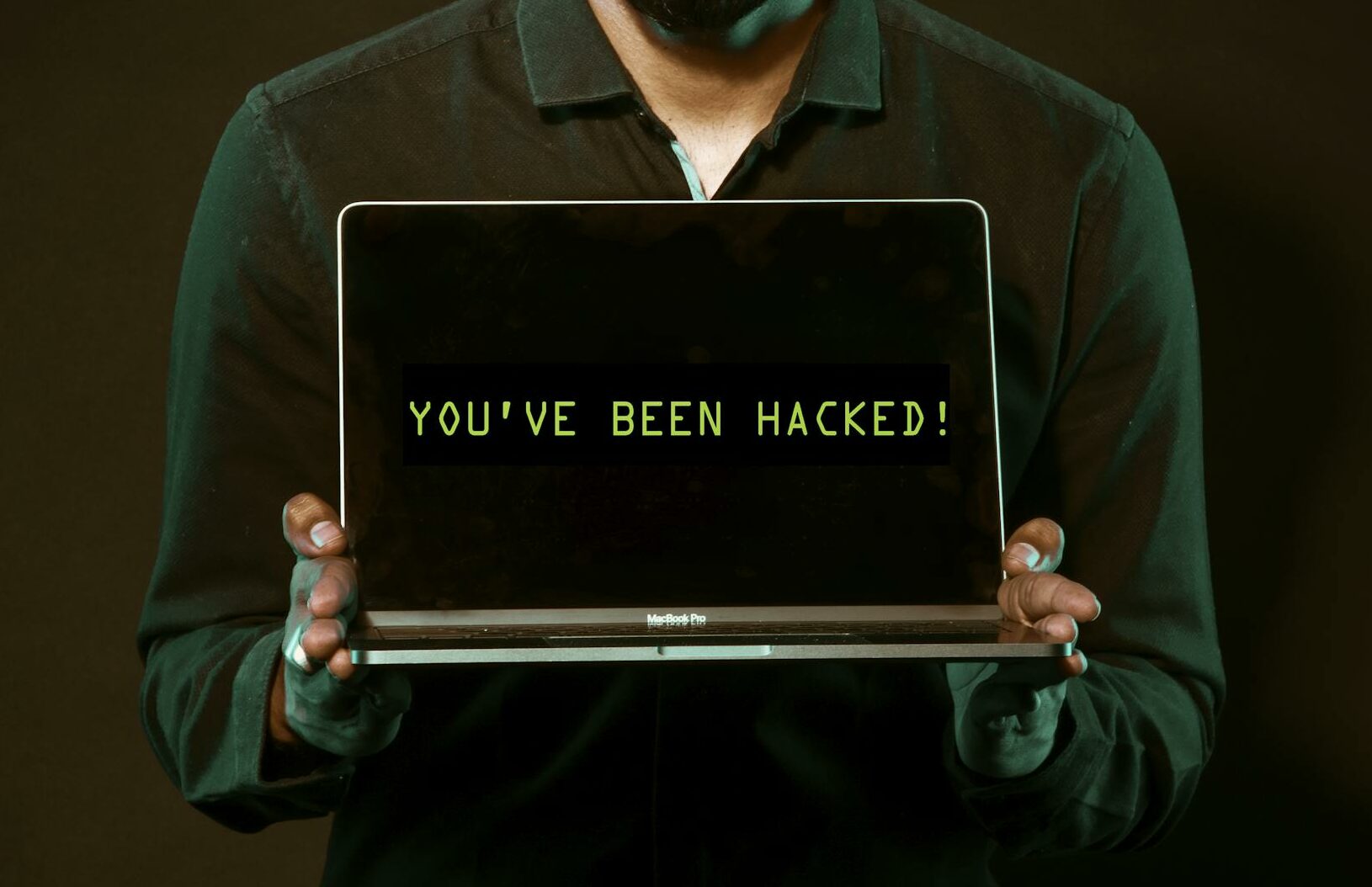 A man showing a laptop with a 'You've been hacked' message, symbolizing cyber security threats.